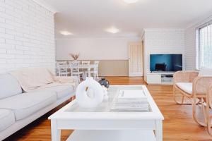 a living room with a white couch and a table at Seaside Haven, 3-62 Tomaree Rd - Wi-Fi and perfect for families in Shoal Bay