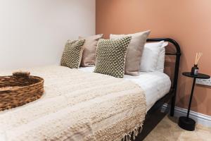 ein Bett mit Kissen und einem Korb darauf in der Unterkunft Wych Cottage, Striking 2 Bed, Parking, King Bed, First Floor Flat in Somerton