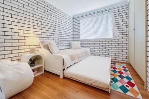 a bedroom with white brick walls and a white chair at Seaside Haven, 3-62 Tomaree Rd - Wi-Fi and perfect for families in Shoal Bay