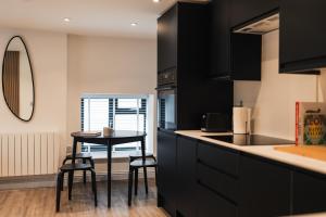 a kitchen with black cabinets and a table with stools at Wych Cottage, Striking 2 Bed, Parking, King Bed, First Floor Flat in Somerton