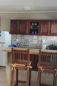 a kitchen with wooden cabinets and two chairs at a counter at La Rosadita House in Jardín América