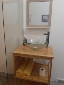 un lavabo de cristal en una mesa de madera con espejo en Zabriko delair en Sainte-Anne