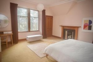 ein Schlafzimmer mit einem weißen Bett und einem Kamin in der Unterkunft Ardchoile, Cairngorms - Escape Cottages Scotland in Kingussie