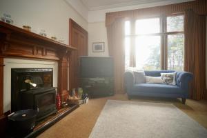 a living room with a blue chair and a television at Ardchoile, Cairngorms - Escape Cottages Scotland in Kingussie