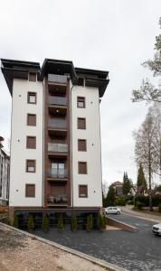 een hoog wit gebouw met ramen aan een straat bij Apartmani Oktobar 06 in Zlatibor