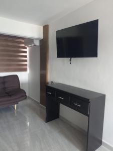 a living room with a tv on the wall and a chair at Departamento centro Zihuatanejo in Zihuatanejo