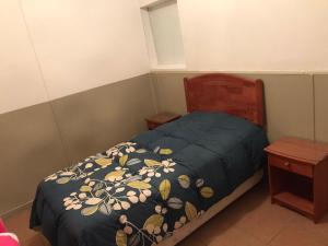 a small bedroom with a bed with a blue comforter at POSADA COPACABANA in Tocopilla