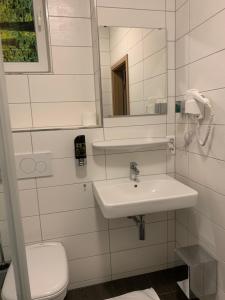 a white bathroom with a sink and a toilet at Hotel Pizzeria Da Beni in Kochersteinsfeld
