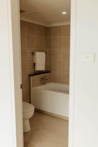 a bathroom with a bath tub and a toilet at Vida Central - 2 bed, 1.5 bath w parking, gym & pool in Newcastle