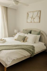 una camera da letto con un grande letto bianco con cuscini bianchi di Vida Central - 2 bed, 1.5 bath w parking, gym & pool a Newcastle