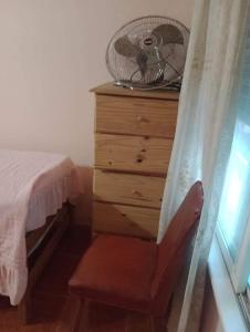 1 dormitorio con vestidor, ventilador y silla en La cabaña en Mar de Ajó