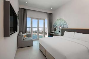 a bedroom with a large bed and a balcony at Rove La Mer Beach, Jumeirah in Dubai