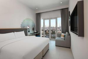 a bedroom with a large white bed and a window at Rove La Mer Beach, Jumeirah in Dubai