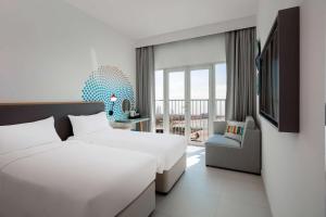 a hotel room with two beds and a window at Rove La Mer Beach, Jumeirah in Dubai