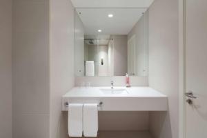 a white bathroom with a sink and a mirror at Rove La Mer Beach, Jumeirah in Dubai