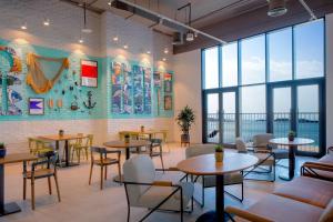a restaurant with tables and chairs and large windows at Rove La Mer Beach, Jumeirah in Dubai