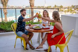 a group of people sitting around a table with drinks at Rove La Mer Beach, Jumeirah in Dubai