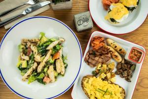 three plates of food on a wooden table at Rove La Mer Beach, Jumeirah in Dubai