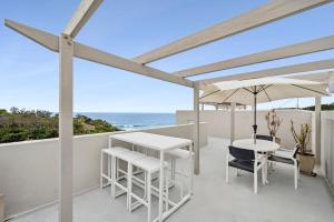 a patio with an umbrella and a table and chairs at Ocean view unit with Private Rooftop in Yaroomba +6 photos
