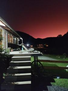 uma vista nocturna de uma casa com uma mesa e escadas em Pousada Nó de Pinho em Urubici