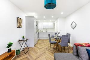 een woonkamer met een tafel en stoelen en een keuken bij 4bed large modern near elizabeth line west london flat free parking in Londen
