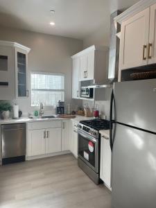 a kitchen with white cabinets and a black refrigerator at Van Nuys Luxury, near to Universal Studios, and Hollywood in Los Angeles