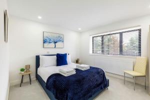 een slaapkamer met een blauw en wit bed en een raam bij 4bed large modern near elizabeth line west london flat free parking in Londen