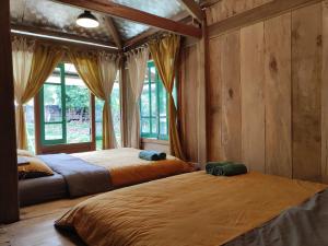 two beds in a room with wooden walls and windows at Little House in KhauPha 