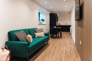 ein Wohnzimmer mit einem grünen Sofa und einem Tisch in der Unterkunft Wych Cottage, Striking 2 Bed, Parking, Ground Floor Flat - Step Free in Somerton