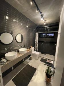 a bathroom with two sinks and a toilet and mirrors at Pousada IMcasa 430 in Bento Gonçalves