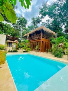 a house with a swimming pool in front of a building at Lodge Tzunum Jade in Tulum