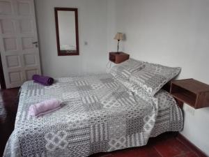 1 dormitorio con 1 cama con edredón blanco y gris en Casa del Bosque en Mar del Plata