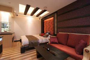 ホテル　Kirara في Kurosu: غرفة نوم بسرير واريكة حمراء