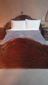 a wooden bed with white pillows and a wooden head board at RIYAD ZENAGA in Figuiq