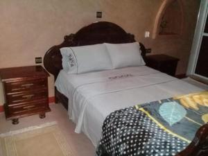 a bedroom with a large bed and a night stand at RIYAD ZENAGA in Figuiq