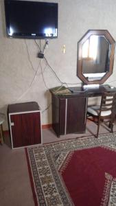 a room with a tv and a desk with a mirror at RIYAD ZENAGA in Figuiq