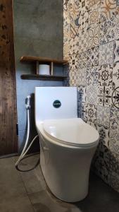 a white toilet in a bathroom with tiles at Little House in KhauPha 