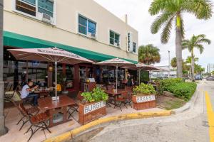 ein Restaurant mit Tischen und Sonnenschirmen vor einem Gebäude in der Unterkunft 6768 Collins Miami Stays in Miami Beach