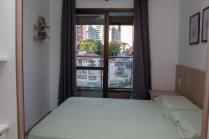 ein Schlafzimmer mit einem Bett und einem großen Fenster in der Unterkunft Salvador / Perto do Shopping Salvador e Shopping da Bahia / Caminho das Árvores in Salvador