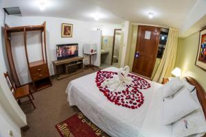 ein Schlafzimmer mit einem weißen Bett mit einer roten Blume darauf in der Unterkunft El Cumbe Inn in Cajamarca