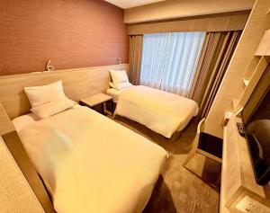 a hotel room with two beds and a window at Hotel Rose Garden Shinjuku in Tokyo