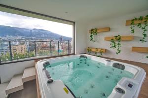 a hot tub in a room with a large window at Moderna suite en Quito RG in Quito