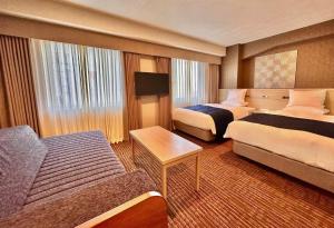 a hotel room with two beds and a couch at Hotel Rose Garden Shinjuku in Tokyo