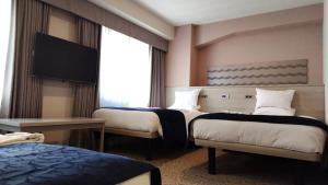 a hotel room with two beds and a flat screen tv at Hotel Rose Garden Shinjuku in Tokyo