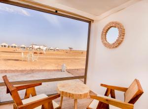 een kamer met een groot raam met een tafel en stoelen bij Sahara Royal Resort in Merzouga