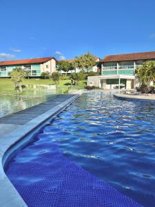 a swimming pool with blue water in front of a building at Flat 707 Villa Hípica Gravatá PE in Gravatá