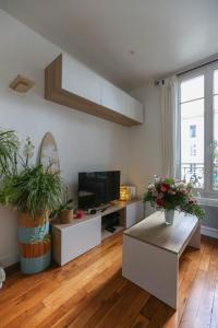 een woonkamer met 2 tafels en een flatscreen-tv bij Comfortable and well-appointed 30 m apartment in Vanves