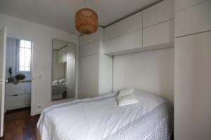 een witte slaapkamer met een bed en een spiegel bij Comfortable and well-appointed 30 m apartment in Vanves