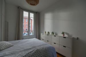 een witte slaapkamer met een bed en een raam bij Comfortable and well-appointed 30 m apartment in Vanves