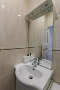 een badkamer met een witte wastafel en een spiegel bij Comfortable and well-appointed 30 m apartment in Vanves